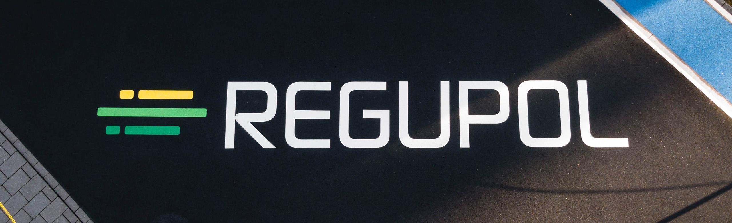 REGUPOL logo in white lettering on black rubber granulate surface, with green and yellow brand bars on the left.